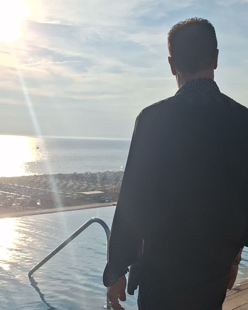 Tom Cummins at a rooftop infinity pool overlooking the sea at sunset