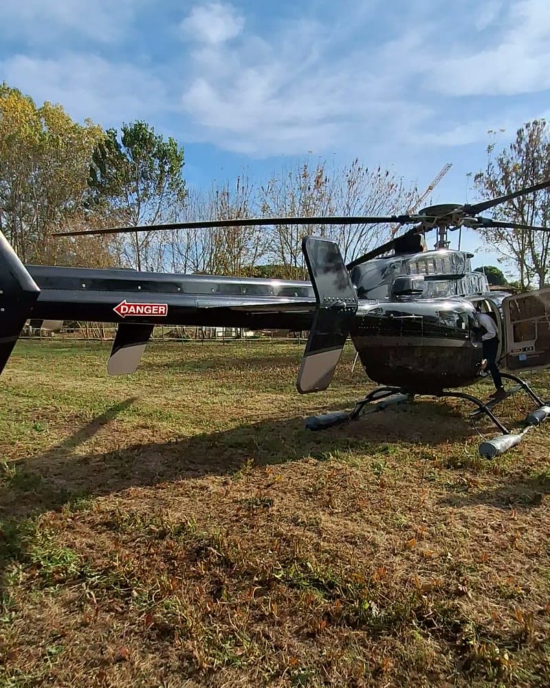 A helicopter resting on a grass field before departure