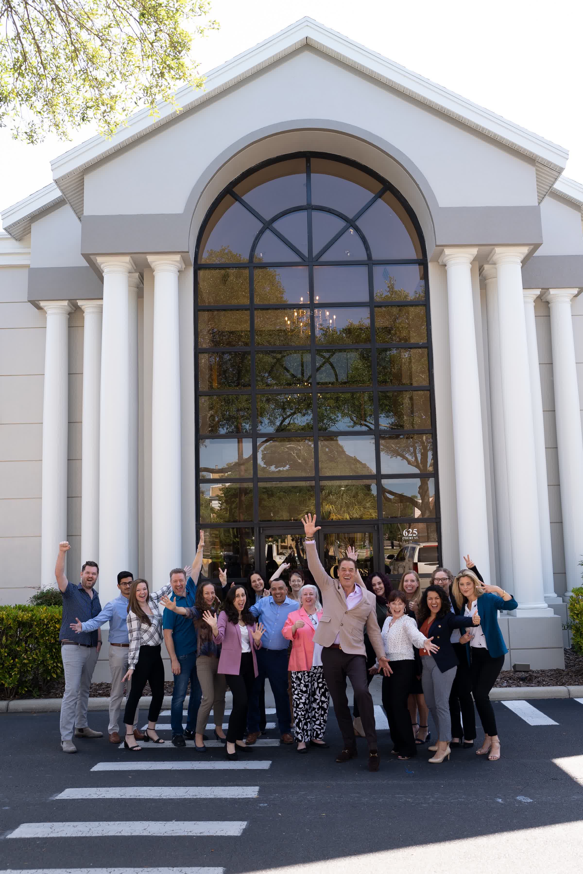 The Cummins Worldwide team celebrating with arms raised outside headquarters